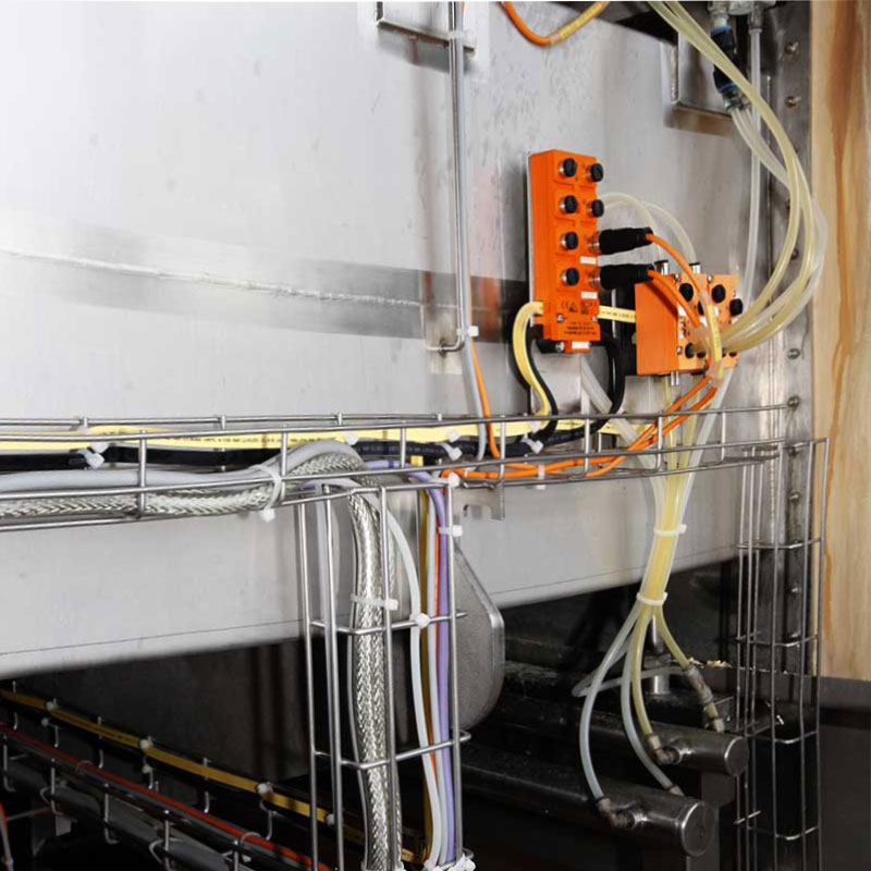 Industriële installatie met zware kabelgoten en oranje besturingsunit